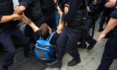 Man being forcibly detained by police officers during protest or altercation.
