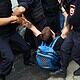 Man being forcibly detained by police officers during protest or altercation.