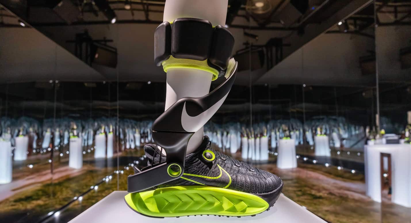 High-tech Nike smart running shoe with attached fitness tracker, displayed in a futuristic exhibit at KnowTechie showcasing innovative wearable technology.