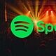 Spotify logo over a concert crowd with stage lights and colorful effects.