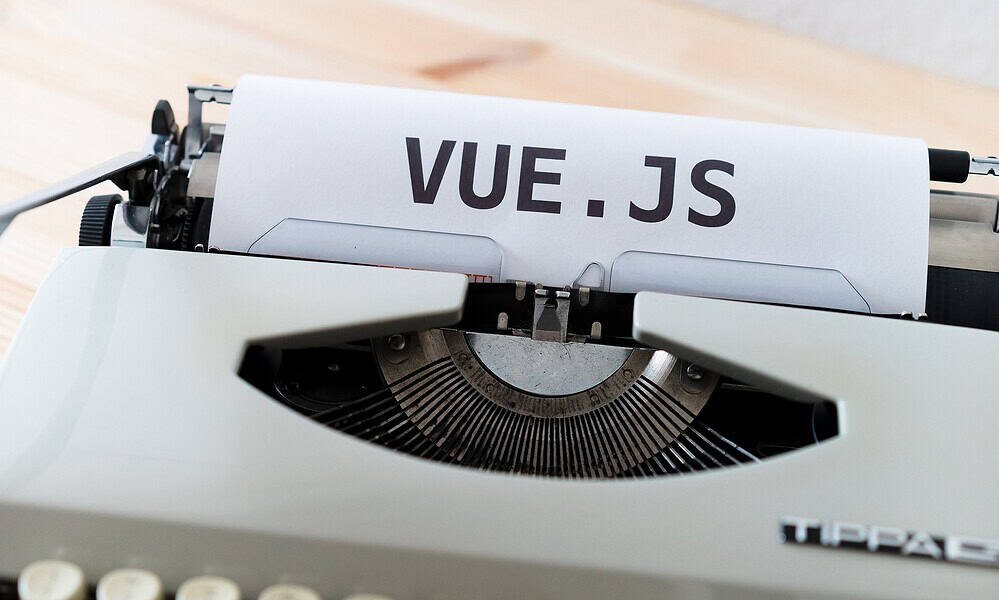 Typewriter with a sheet of paper displaying "VUE.JS" for web development and JavaScript frameworks.
