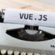 Typewriter with a sheet of paper displaying "VUE.JS" for web development and JavaScript frameworks.
