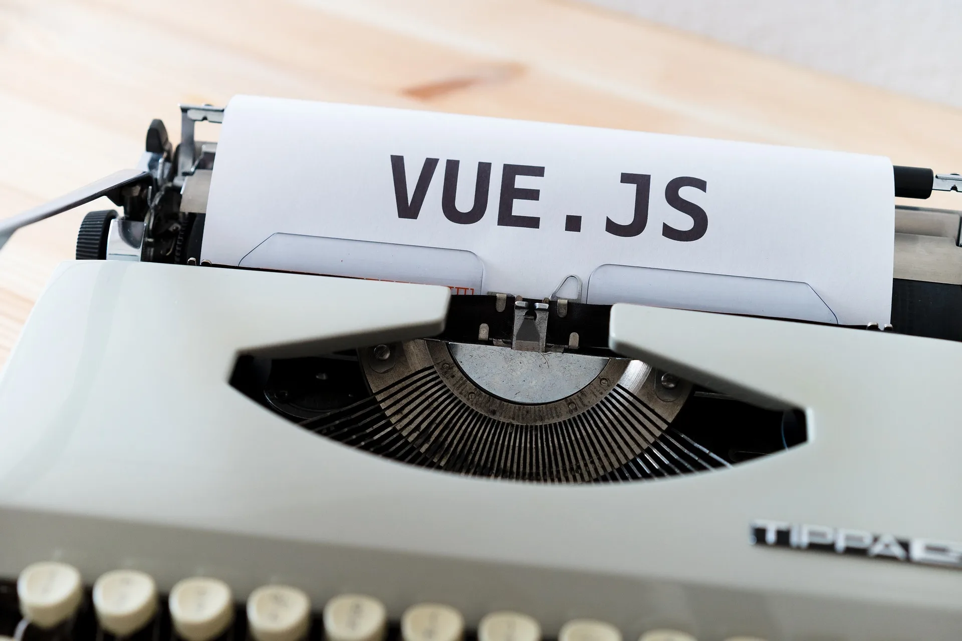 Typewriter with a sheet of paper displaying "VUE.JS" for web development and JavaScript frameworks.
