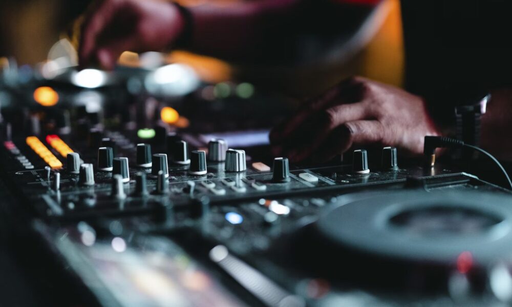 High-quality image of a DJ mixing music at a nightclub, showcasing professional DJ equipment with colorful LED lights, creating an energetic atmosphere for electronic dance music events.