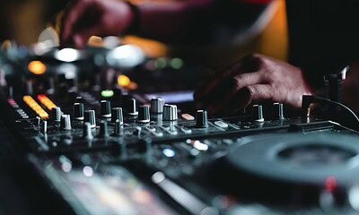 High-quality image of a DJ mixing music at a nightclub, showcasing professional DJ equipment with colorful LED lights, creating an energetic atmosphere for electronic dance music events.
