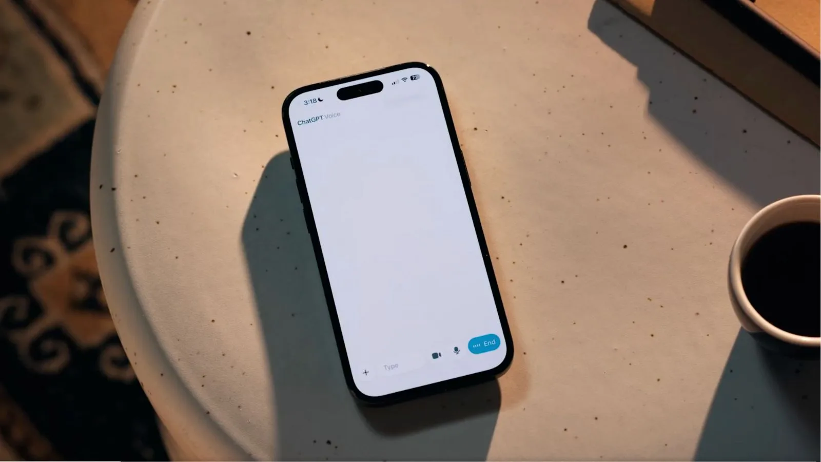 Smartphone with ChatGPT voice app open, ready for conversation, on a beige table with coffee cup nearby, showcasing AI technology and digital assistant features for modern communication.