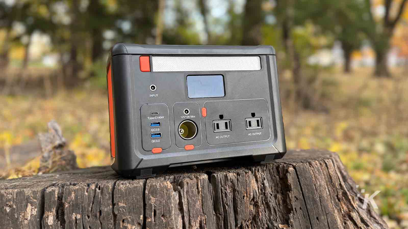 Portable power station on a tree stump outdoors.