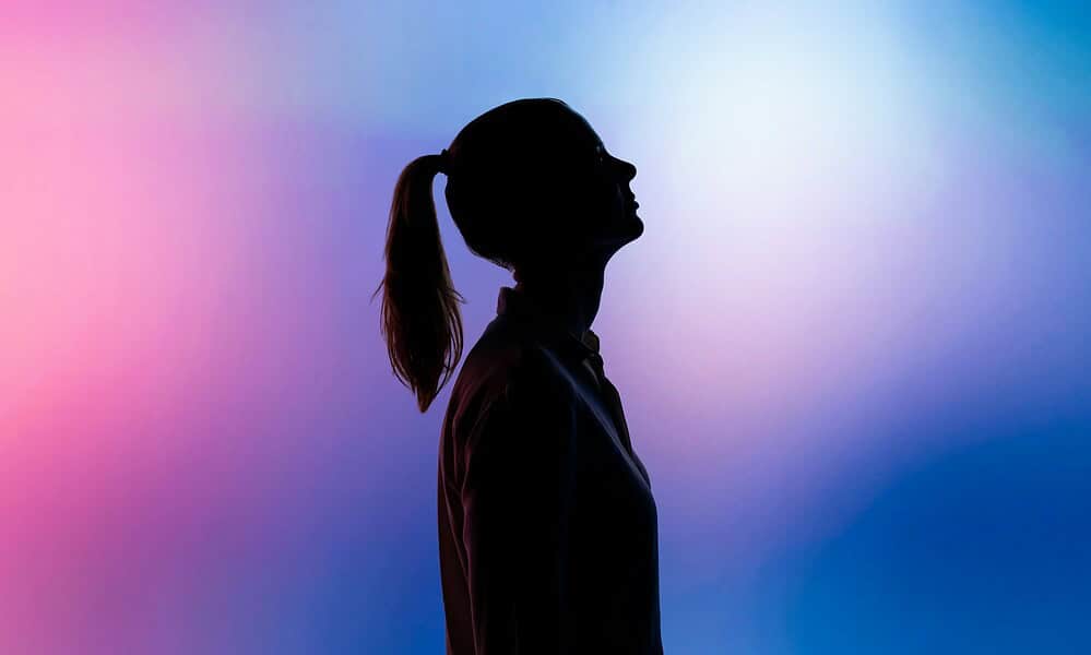 Silhouette of a woman with a ponytail against vibrant pink and blue gradient background, emphasizing technology, innovation, and modern lifestyle themes for SEO optimization.