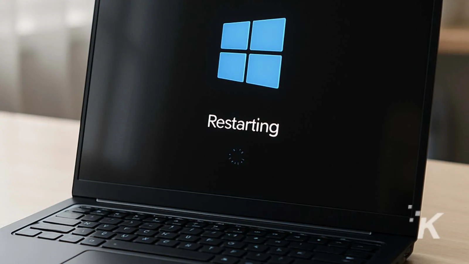 Blue Windows logo on a black laptop screen showing restarting message.