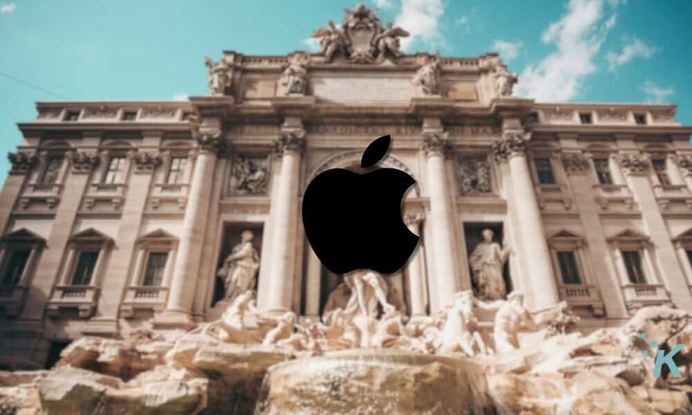 Bold black Apple logo overlay on historic building, showcasing Apple's iconic branding and modern technology presence in Rome with classical architecture and clear blue sky.