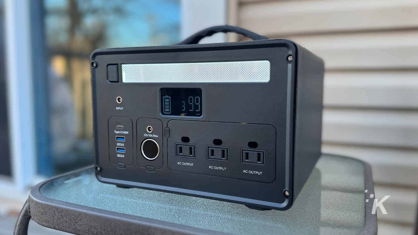 Portable solar generator with multiple AC outputs on table.