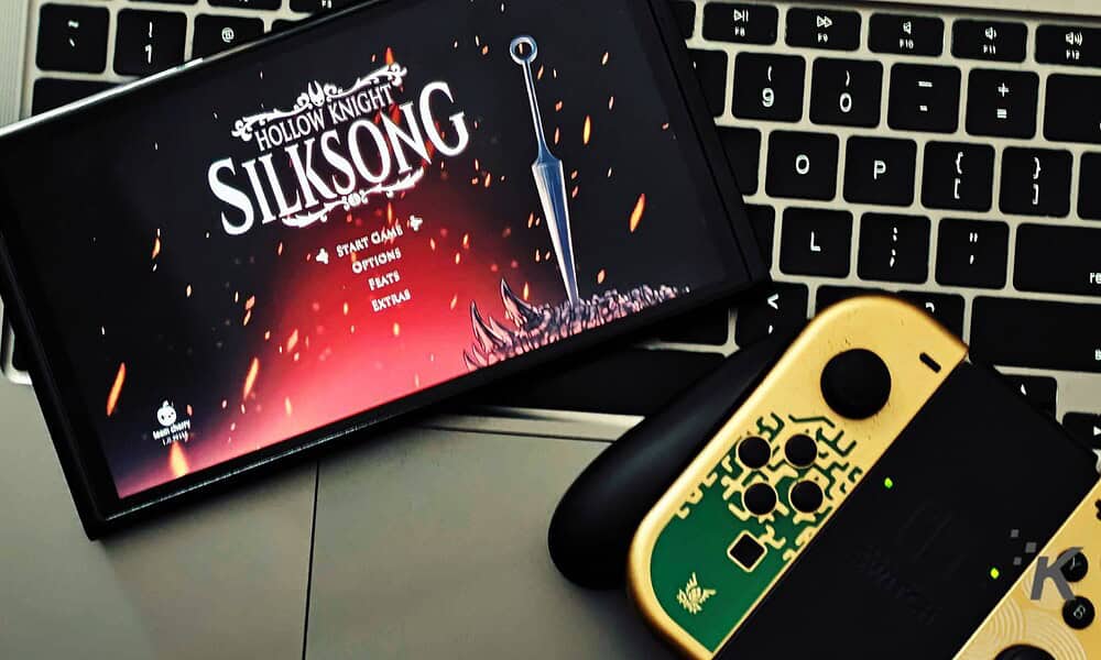 Vivid image of the Silksonic game menu displayed on a smartphone screen, with Nintendo Switch controllers and a keyboard in the background, highlighting gaming accessories and entertainment technology.