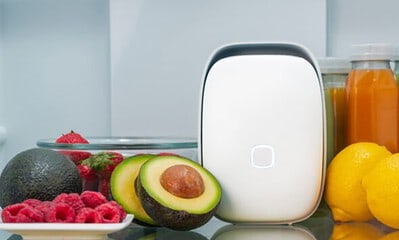 A sleek, modern smart refrigerator with a digital interface, surrounded by fresh fruits like avocados, lemons, berries, and bottles of juice, showcasing advanced kitchen tech.
