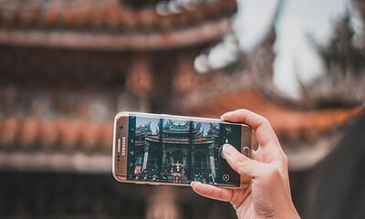 Close-up of a person taking a photo of a traditional temple using a Samsung smartphone, highlighting advancements in mobile photography and cultural photo opportunities.