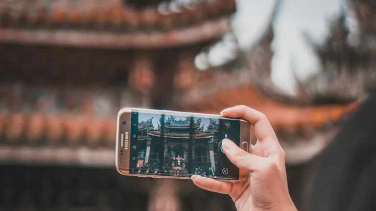 Close-up of a person taking a photo of a traditional temple using a Samsung smartphone, highlighting advancements in mobile photography and cultural photo opportunities.