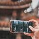 Close-up of a person taking a photo of a traditional temple using a Samsung smartphone, highlighting advancements in mobile photography and cultural photo opportunities.