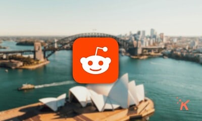 Reddit logo displayed prominently against a blurred background of Sydney’s iconic bridge and Opera House, emphasizing social media, discussion forums, and internet culture.
