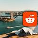 Reddit logo displayed prominently against a blurred background of Sydney’s iconic bridge and Opera House, emphasizing social media, discussion forums, and internet culture.