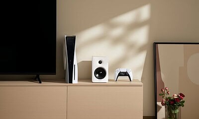 PS5, edifier speaker, and controller on wooden cabinet