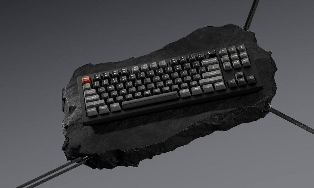 Floating mechanical Keychron keyboard on dark stone surface.