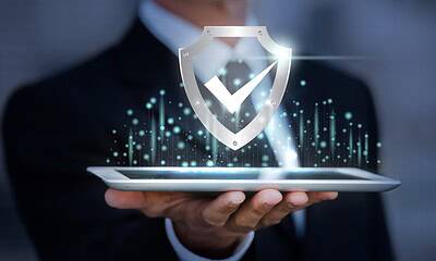 Cybersecurity illustration with shield icon and checkmark displayed above a person's hand holding a tablet, symbolizing digital protection, cyber defenses, and data security in technology.